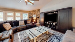 A living room with a sofa, coffee table, fireplace, and a ceiling fan. - Spacious home with private hot tub, Ping-Pong (Sunriver)