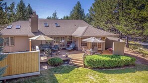 A two-story house with a deck, outdoor seating, and a small pond. - Spacious home with private hot tub, Ping-Pong (Sunriver)