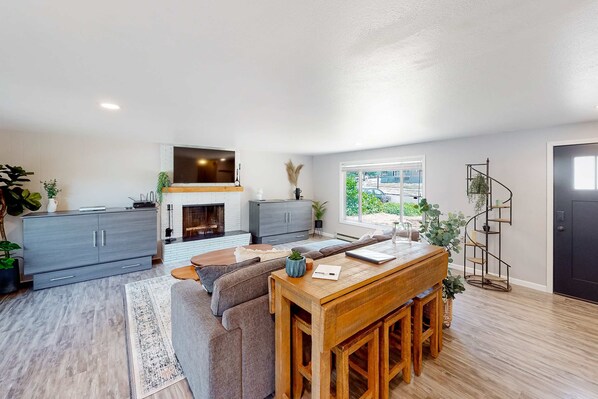 A modern living space with a fireplace, a dining area, and a staircase.
