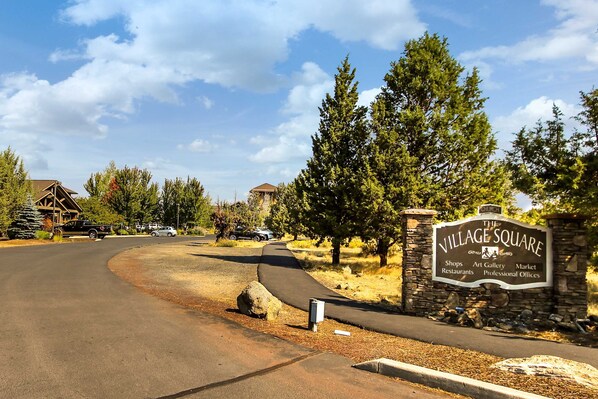 A sign for 'The Village Square' with amenities like shops, art gallery, market, restaurants, and professional offices.
