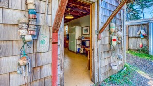 Un bâtiment rustique en bois, doté d’une porte en bois, d’un couloir menant à l’intérieur et de divers objets accrochés aux murs.