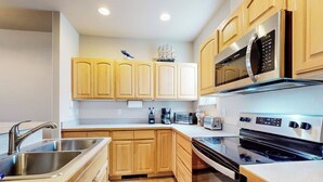 A modern kitchen with wooden cabinets, stainless steel appliances, and a microwave. - Dog-friendly condo with river views, private W&D, full kitchen, & great location (Florence)