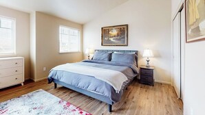 A bedroom with a bed, bedside tables, a dresser, and a painting on the wall. - Dog-friendly condo with river views, private W&D, full kitchen, & great location (Florence)