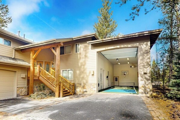 A two-story house with a covered outdoor area, a wooden staircase, and a pool. - Comfortable home with SHARC passes, private hot tub, balcony, & pickleball (Sunriver)