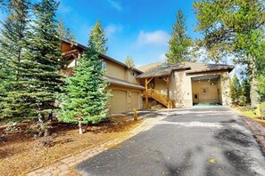 A lodge with a covered entrance, a wooden staircase, and a large evergreen tree. - Comfortable home with SHARC passes, private hot tub, balcony, & pickleball (Sunriver)