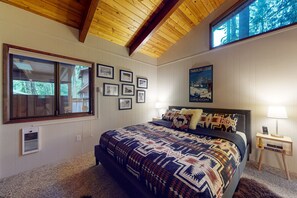 A bedroom with a large bed, a window, and a poster on the wall.