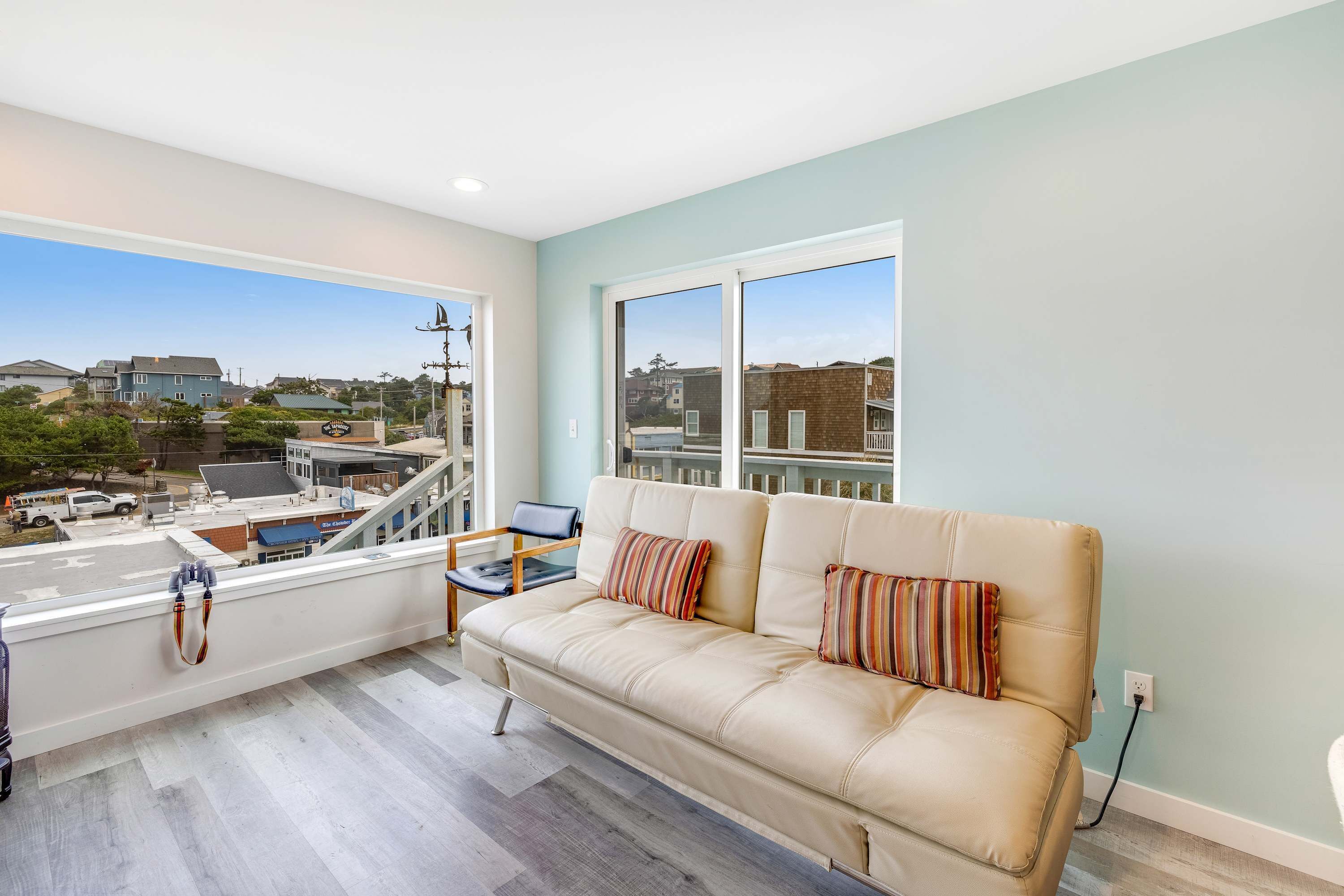 A balcony with a sofa, a chair, and a view of buildings and a street.