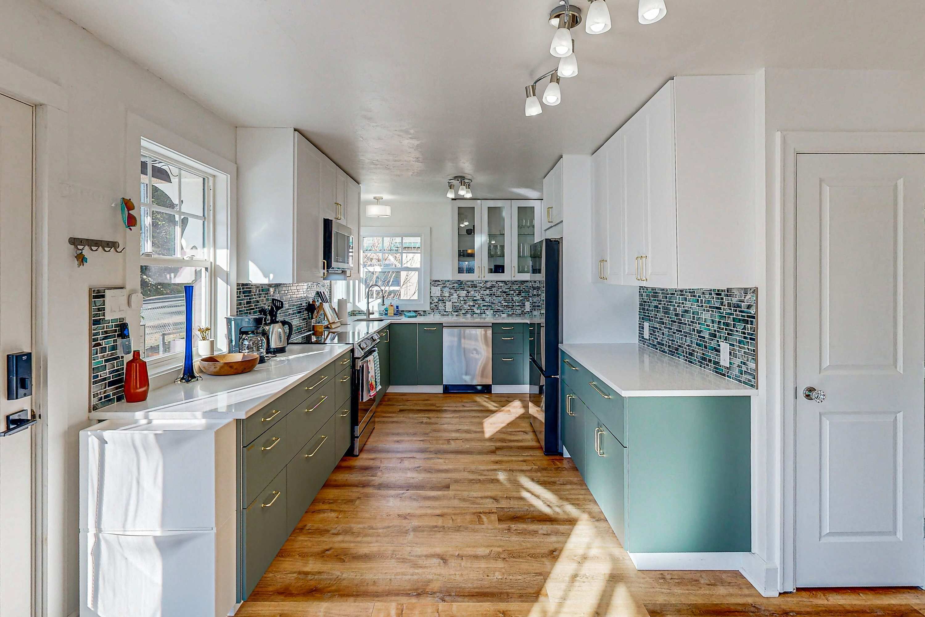 Une cuisine moderne dotée d’un îlot central, d’un plancher en bois et offrant une vue sur l’extérieur.