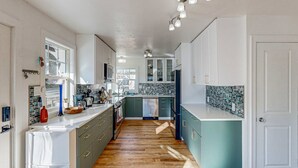 A modern kitchen with a central island, wooden flooring, and a view to the outside. - Renovated home in central location with hot tub, theater, fast wifi & work desks (Stevenson)