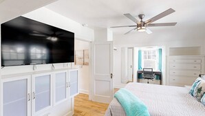 A bedroom with a TV, ceiling fan, white cabinets, a bed, and a desk area. - Renovated home in central location with hot tub, theater, fast wifi & work desks (Stevenson)