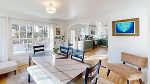 A spacious dining area with a large table, chairs, and a bench. A kitchen is visible in the background. - Renovated home in central location with hot tub, theater, fast wifi & work desks (Stevenson)