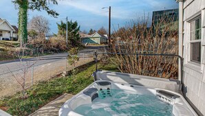 A hot tub with a control panel, a wooden deck, and a view of a road and houses. - Renovated home in central location with hot tub, theater, fast wifi & work desks (Stevenson)