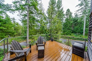 Une terrasse en bois avec une chaise et une table, entourée d’arbres.