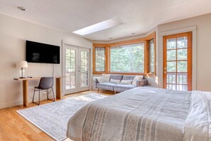 A bedroom with a large bed, a desk, a chair, a TV, and large windows. - Expansive golf-view getaway with private hot tub, pool, fast WiFi & game room (Welches)