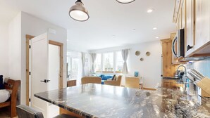 Une cuisine moderne dotée d’un grand îlot central, de meubles en bois et d’un coin repas avec des chaises et un canapé.