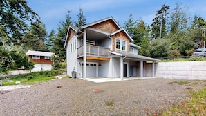Une maison à deux étages avec un balcon, un garage et une allée gravillonnée.