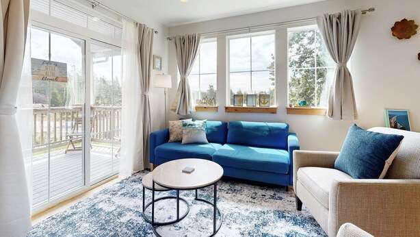 Un salon avec un canapé bleu, une table basse ronde et un fauteuil en osier.