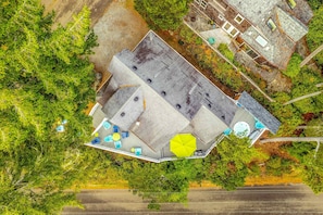 An aerial view of a property with a large deck area, outdoor seating, and a swimming pool. - Classic, dog-friendly beach house with vast outdoor living, hot tub & firepit (Manzanita)