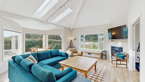 Ein geräumiges Wohnzimmer mit einer Eckcouch, einem Holztisch und einem an der Wand befestigten Fernseher.