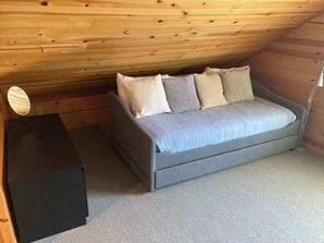 Ein kleiner, gemütlicher Raum mit einem Bett, einem Schreibtisch und einer Lampe.