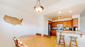 Une cuisine moderne avec des meubles en bois, un îlot central doté de tabourets et une table à manger avec des chaises.