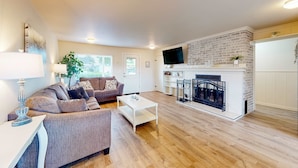 A living room with a fireplace, a sofa, a coffee table, and a TV.