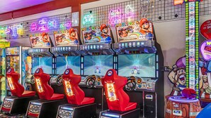 Une rangée de machines de jeux vidéo aux graphismes inspirés de Mario, un panneau lumineux au néon et un comptoir où l’on peut réclamer des prix.