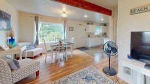 Un salon équipé d’un téléviseur et d’un ventilateur, ainsi qu’un coin repas avec des chaises et une table.