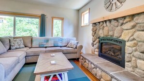 A living room with a stone fireplace, a sectional sofa, and a coffee table. - Kid-friendly house with fireplace, entertainment, and nearby beach access (Manzanita)
