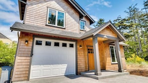 A two-story house with a white garage door, a front porch, and a mailbox. - Kid-friendly house with fireplace, entertainment, and nearby beach access (Manzanita)