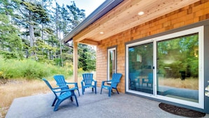 A wooden exterior with a covered patio area featuring four blue Adirondack chairs. - Kid-friendly house with fireplace, entertainment, and nearby beach access (Manzanita)