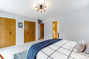 Ein Schlafzimmer mit Bett, Holzschrank und Deckenleuchte.