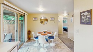 A dining area with a round table and four chairs, a sliding glass door, and a small potted plant. - Upper level of duplex with a large deck & mountain view - dog friendly for 1 dog (Eugene)