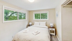 A bedroom with a bed, two bedside tables, two windows, and a ceiling light. - Upper level of duplex with a large deck & mountain view - dog friendly for 1 dog (Eugene)