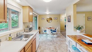 A kitchen with a sink, countertop, and a dining area with a table and chairs. - Upper level of duplex with a large deck & mountain view - dog friendly for 1 dog (Eugene)