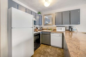 A compact kitchen with a refrigerator, microwave, stove, dishwasher, and grey cabinets. - Convenient oceanfront studio condo with ocean view and seasonal pool (Newport)
