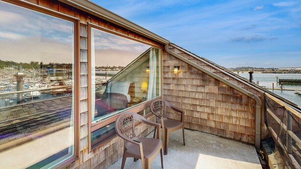 Un balcon donnant sur une marina, des murs en bois et deux chaises.