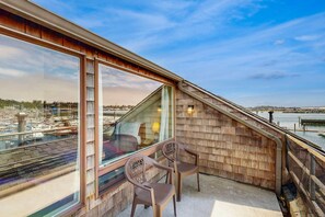 A balcony with a view of a marina, wooden walls, and two chairs. - Family-Friendly Waterfront Studio with High-Speed WiFi, Marina View, & Kitchenette (Newport)