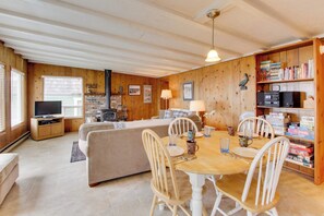 Une pièce confortable avec une table à manger, des chaises, un téléviseur et une bibliothèque.