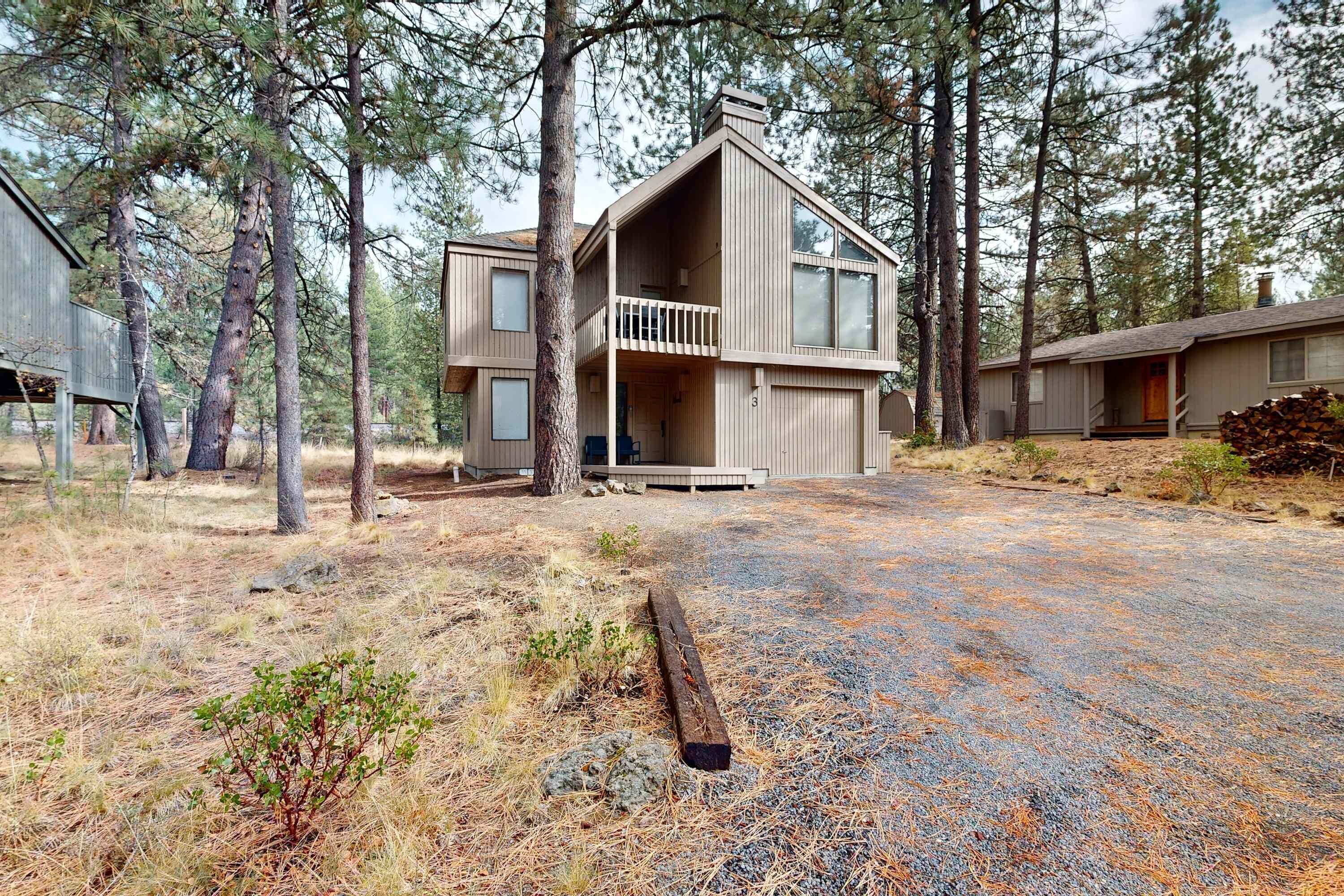 A two-story cabin with a balcony, surrounded by tall pine trees.