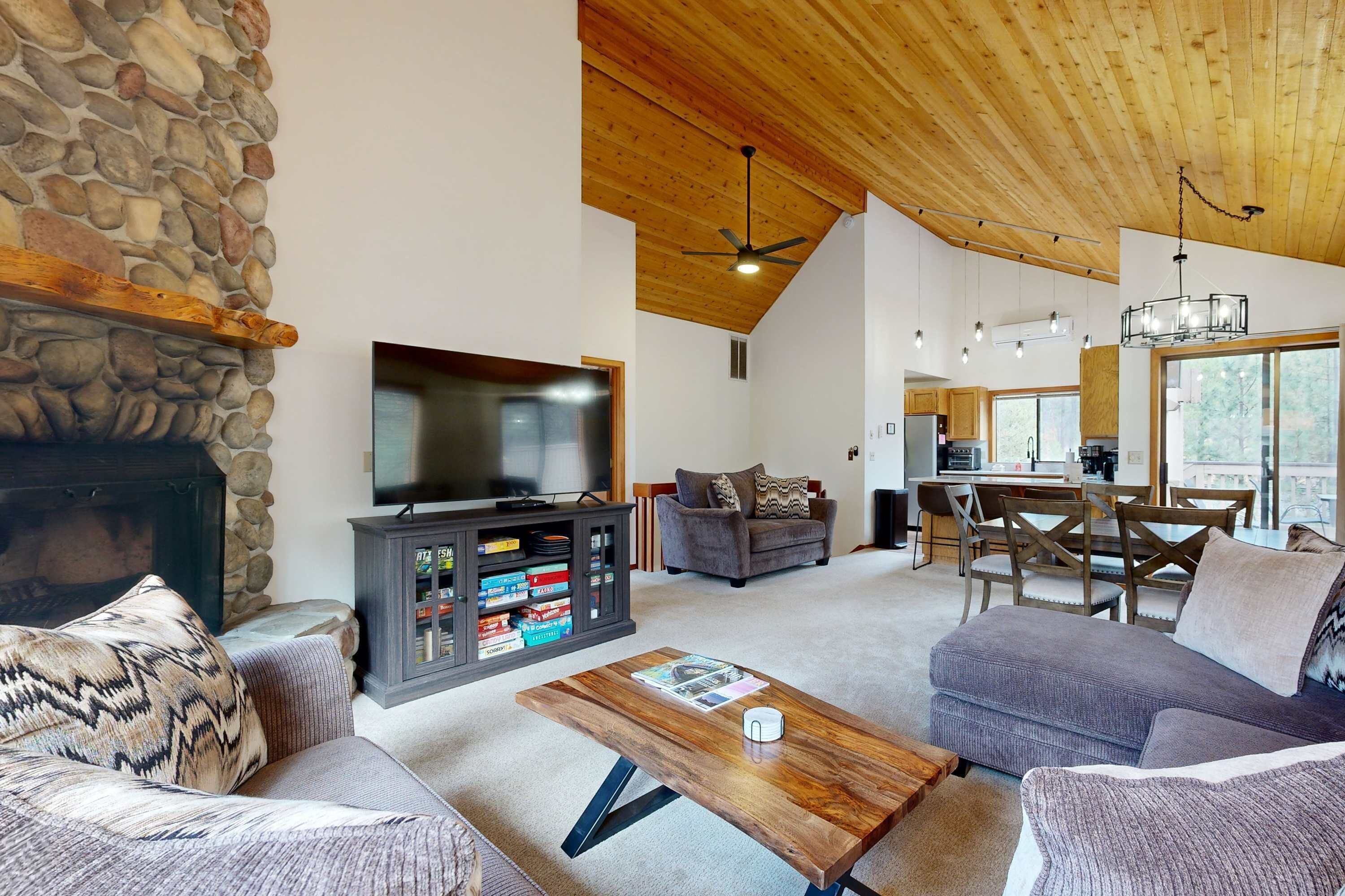 A spacious living room with a stone fireplace, a flat-screen TV, and a cozy seating area.