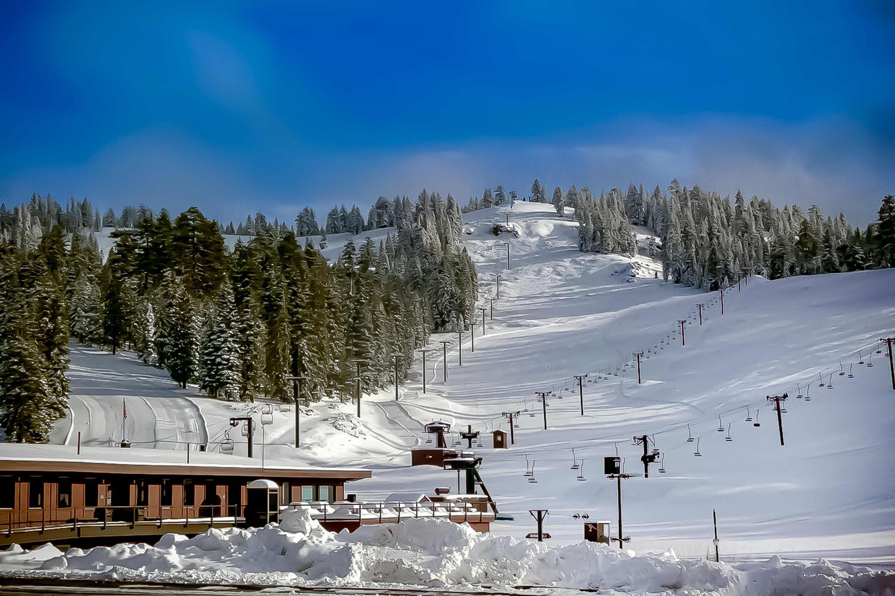 A snow-covered ski slope with a building and ski lift infrastructure.