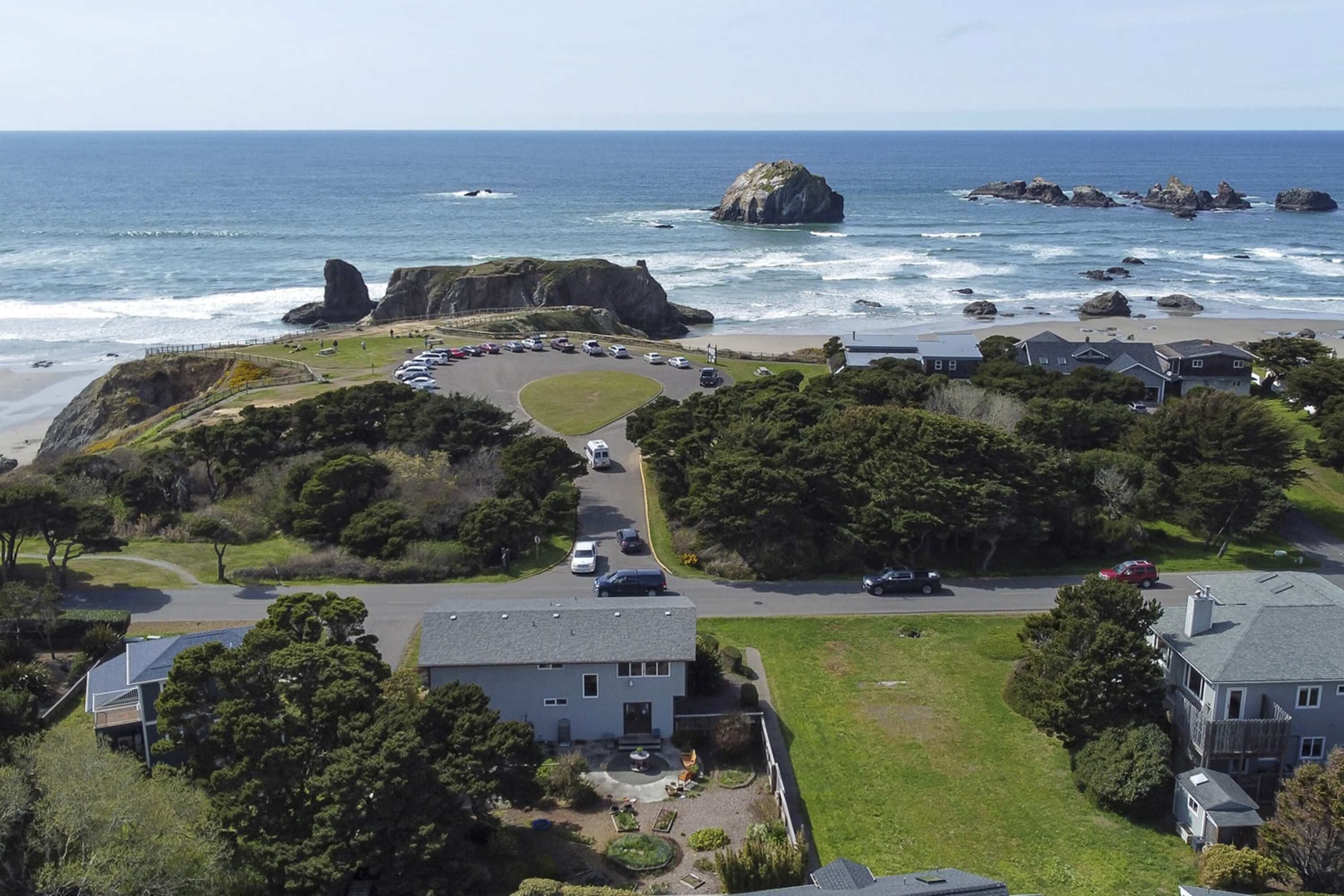 A coastal residential area with houses, a parking lot, and a beach.
