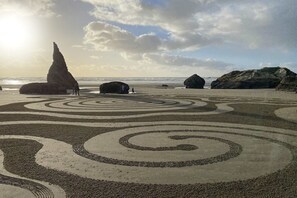 A beach with large rocks and spiral patterns on the sand. - Charming dog-friendly home with ocean-view, beach access, & washer/dryer (Bandon)