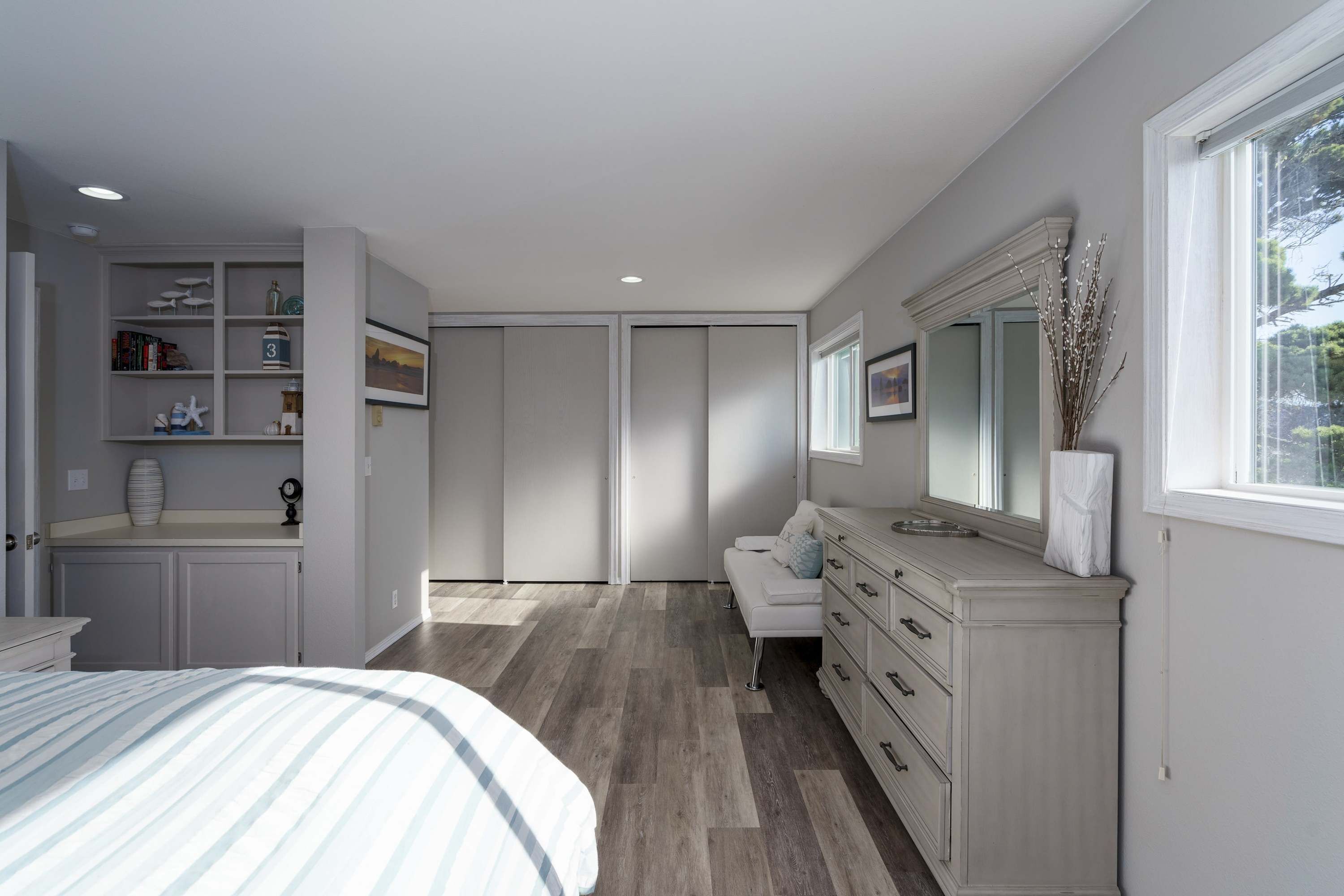 A bedroom with a bed, dresser, vanity, and a closet.