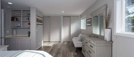 A bedroom with a bed, dresser, vanity, and a closet.