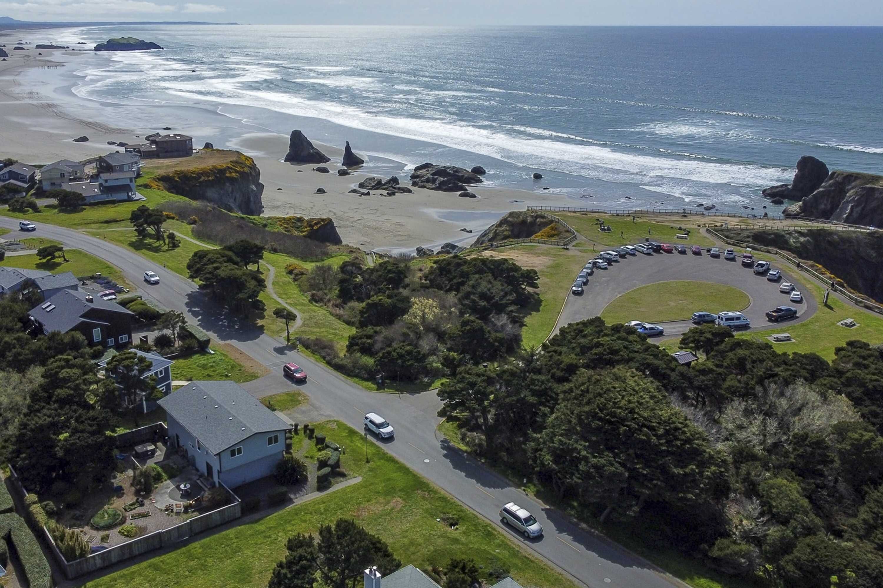 Vue aérienne d’une zone côtière avec des maisons, une route et une plage.