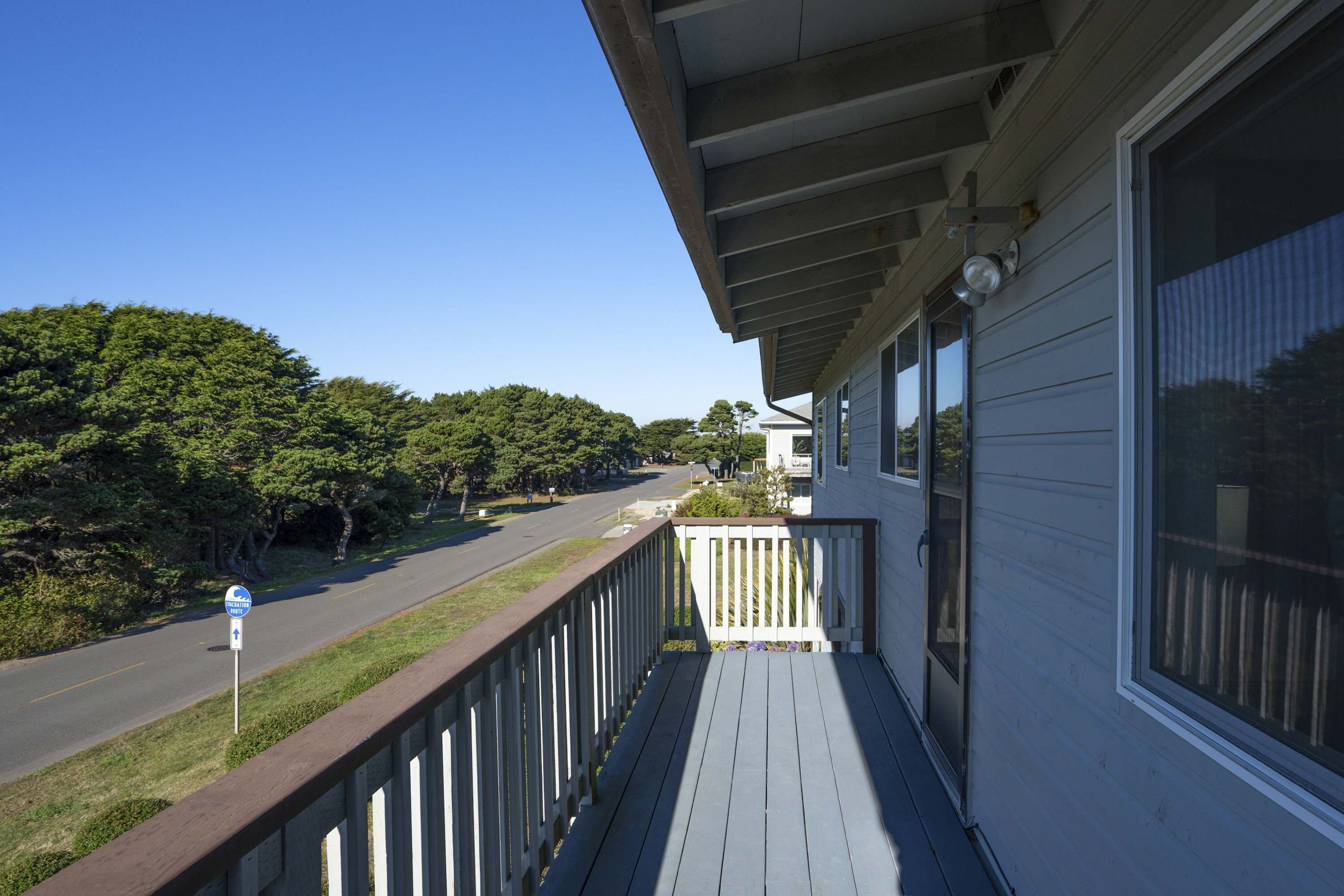 A house with a porch, a road, and trees in the background.