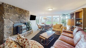 Ein Wohnzimmer mit Steinwand, Kamin, Ledersofa, Couchtisch und einem Essbereich mit Stühlen.