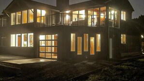 Ein zweistöckiges Gebäude mit großen Fenstern, einem Balkon und einer Garage.